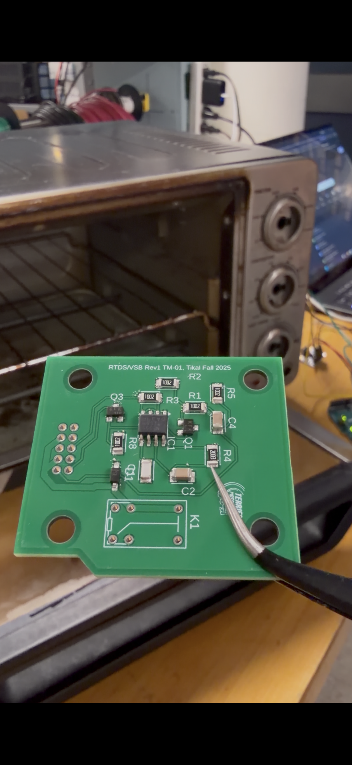 Reflowed PCB with SMD components held up in front of the reflow oven